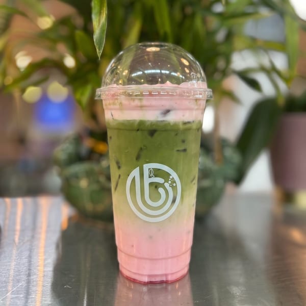 A vibrant layered drink with pink at the bottom, white in the middle, and green on top.