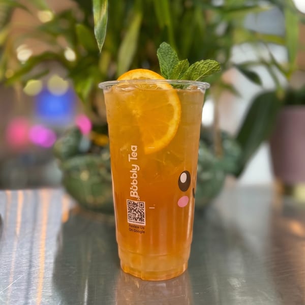 Bubbly Tea's iced orange drink with a fresh orange slice and mint garnish.