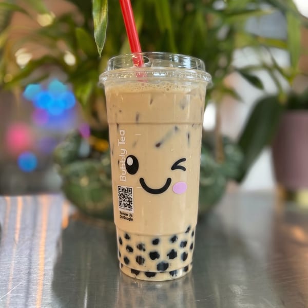 Bubbly Tea's iced milk tea with boba, a red straw, and a winking face logo.